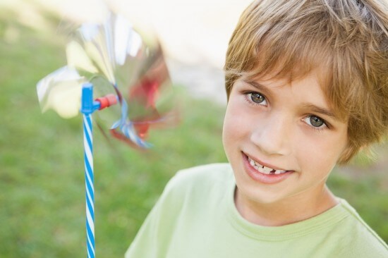Close-up portrait of a smiling boy holding pinwheel in the park