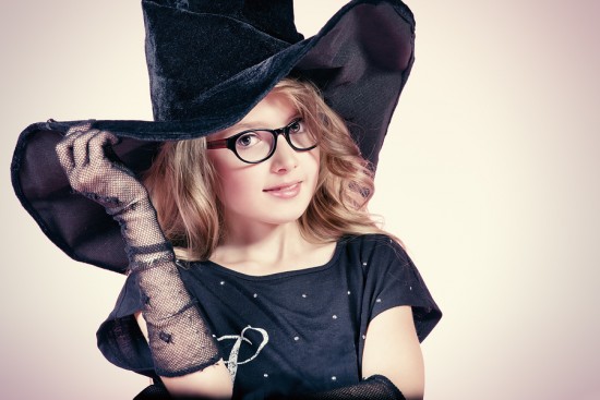 Pretty ten years girl in a witch costume smiling at camera. Pink